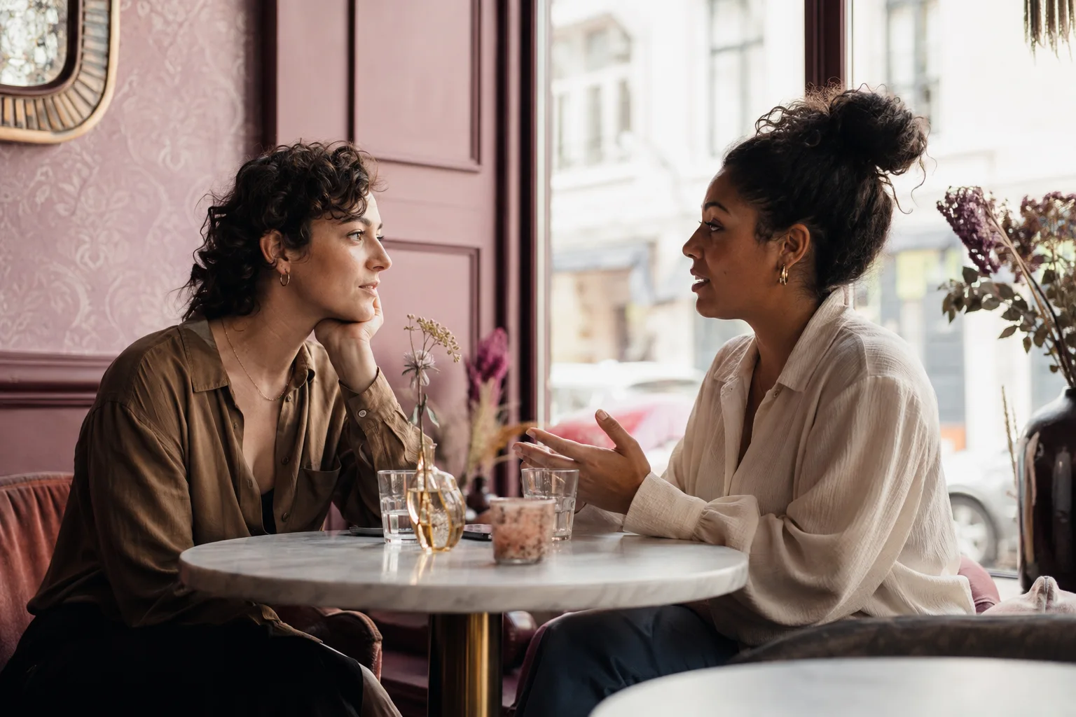Twee volwassenen die ontspannen met elkaar praten in een kleurrijk café.